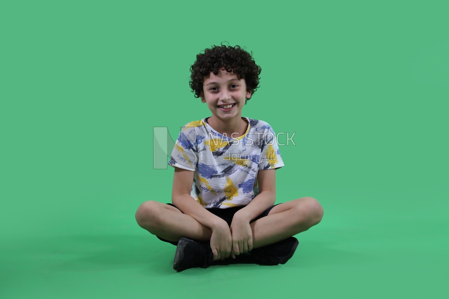 A boy sitting in a green background