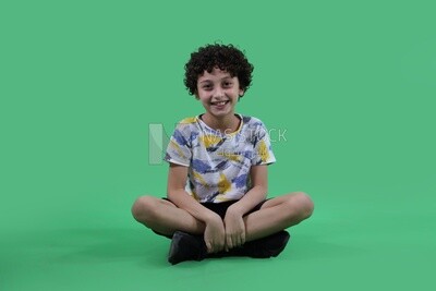 A boy sitting in a green background