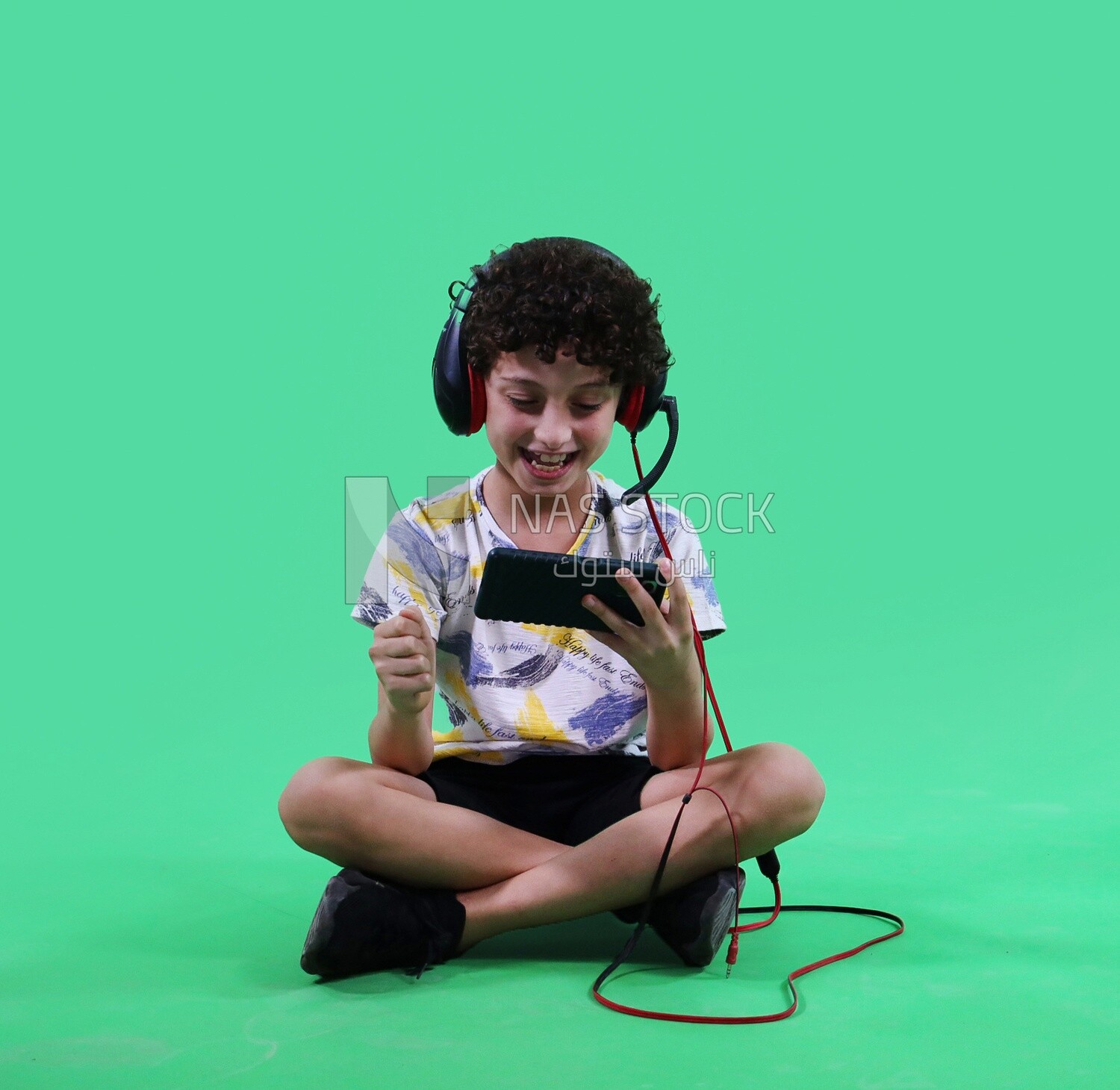 A boy holding a tablet and wearing a headphone