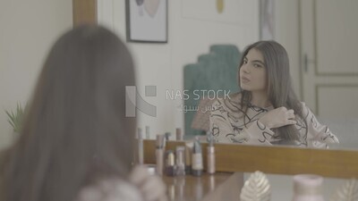a woman sitting in front of the mirror brushing her hair
