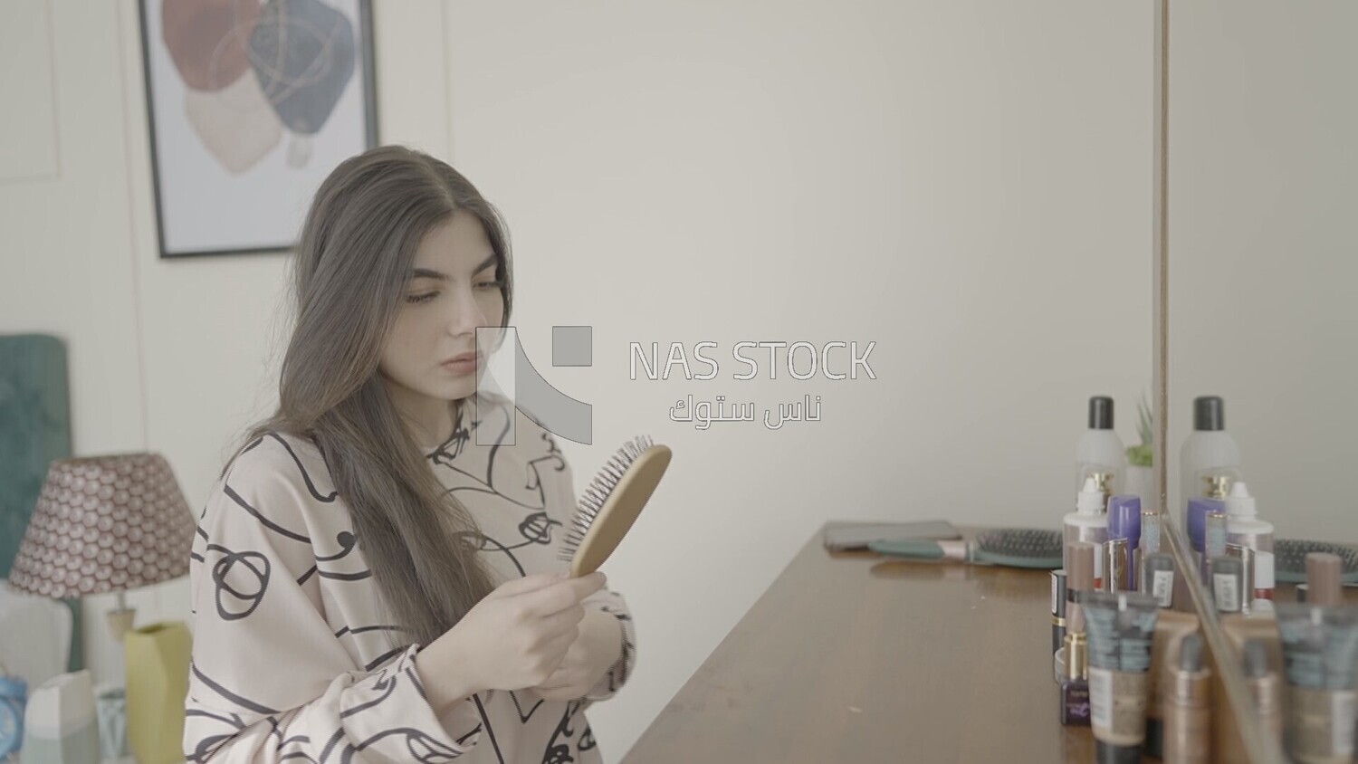 a woman sitting in front of the mirror brushing her hair