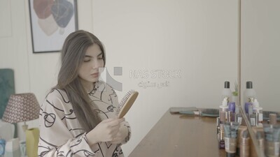 امراة تجلس امام المرأة تمشط شعرها 