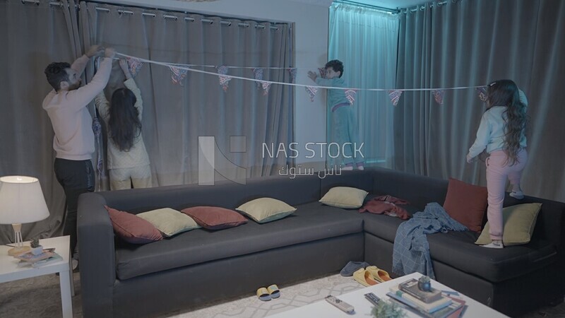 a family of four hanging the ramadan decoration in the living room