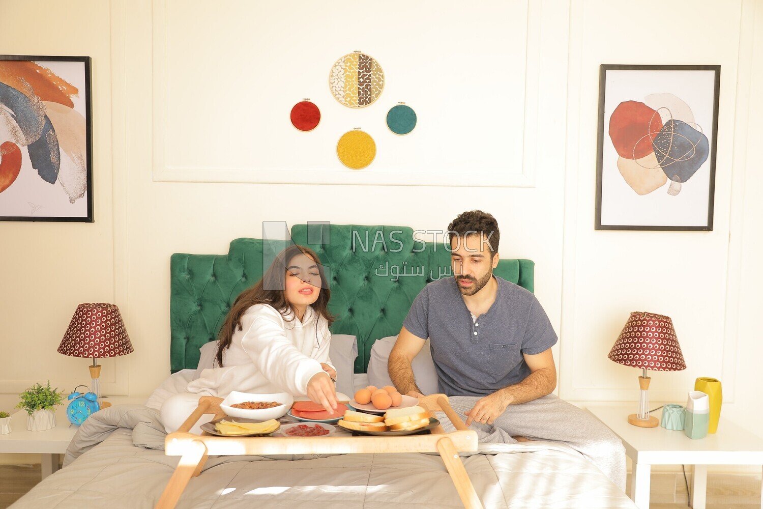 a man and a woman having breakfast on the bed