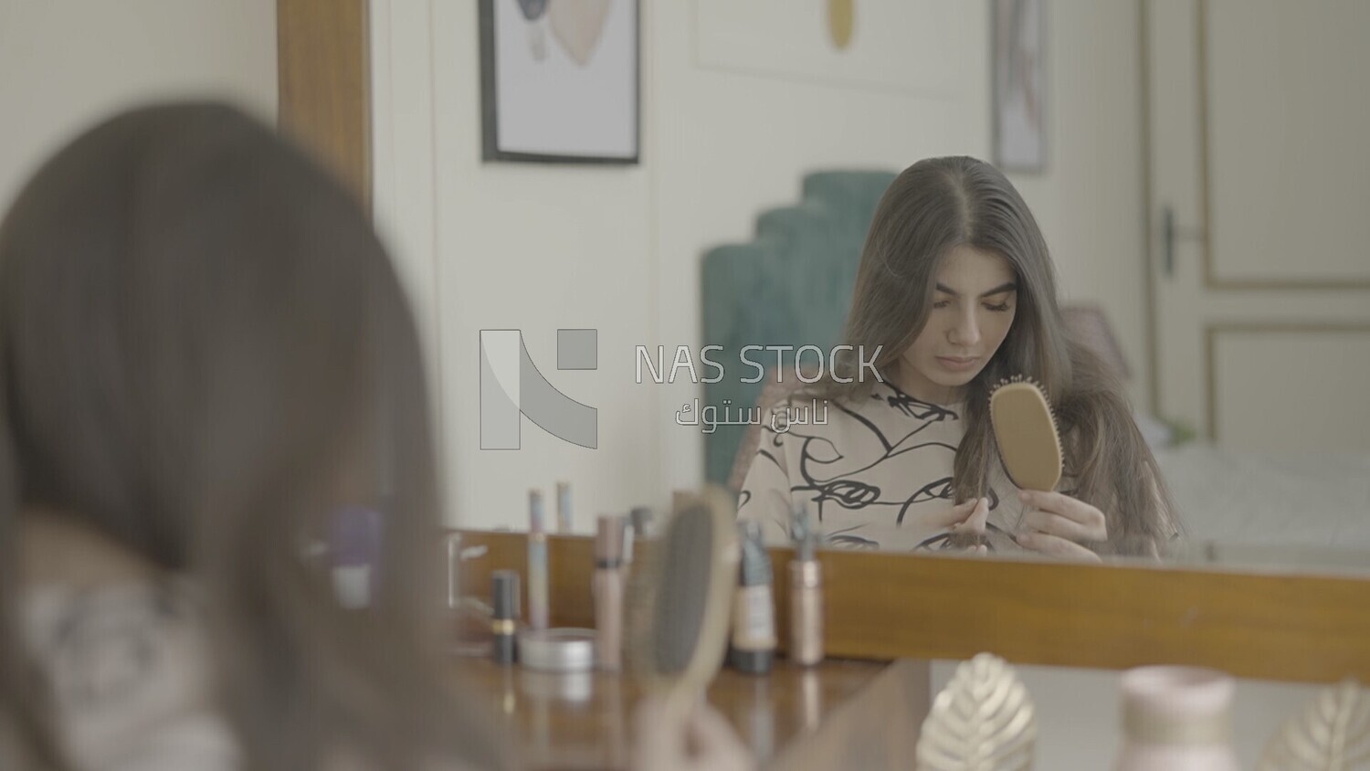 a woman sitting in front of the mirror brushing her hair