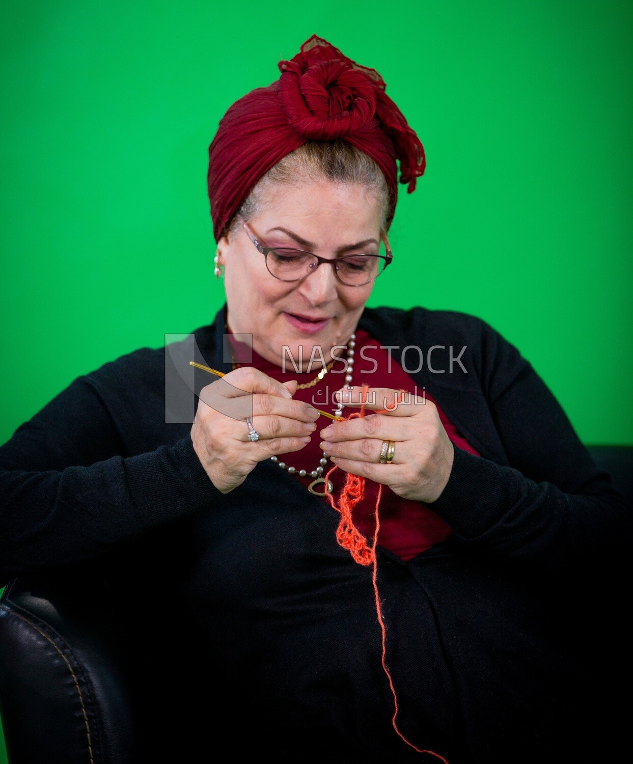 An elderly woman making crochet