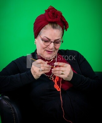 An elderly woman making crochet