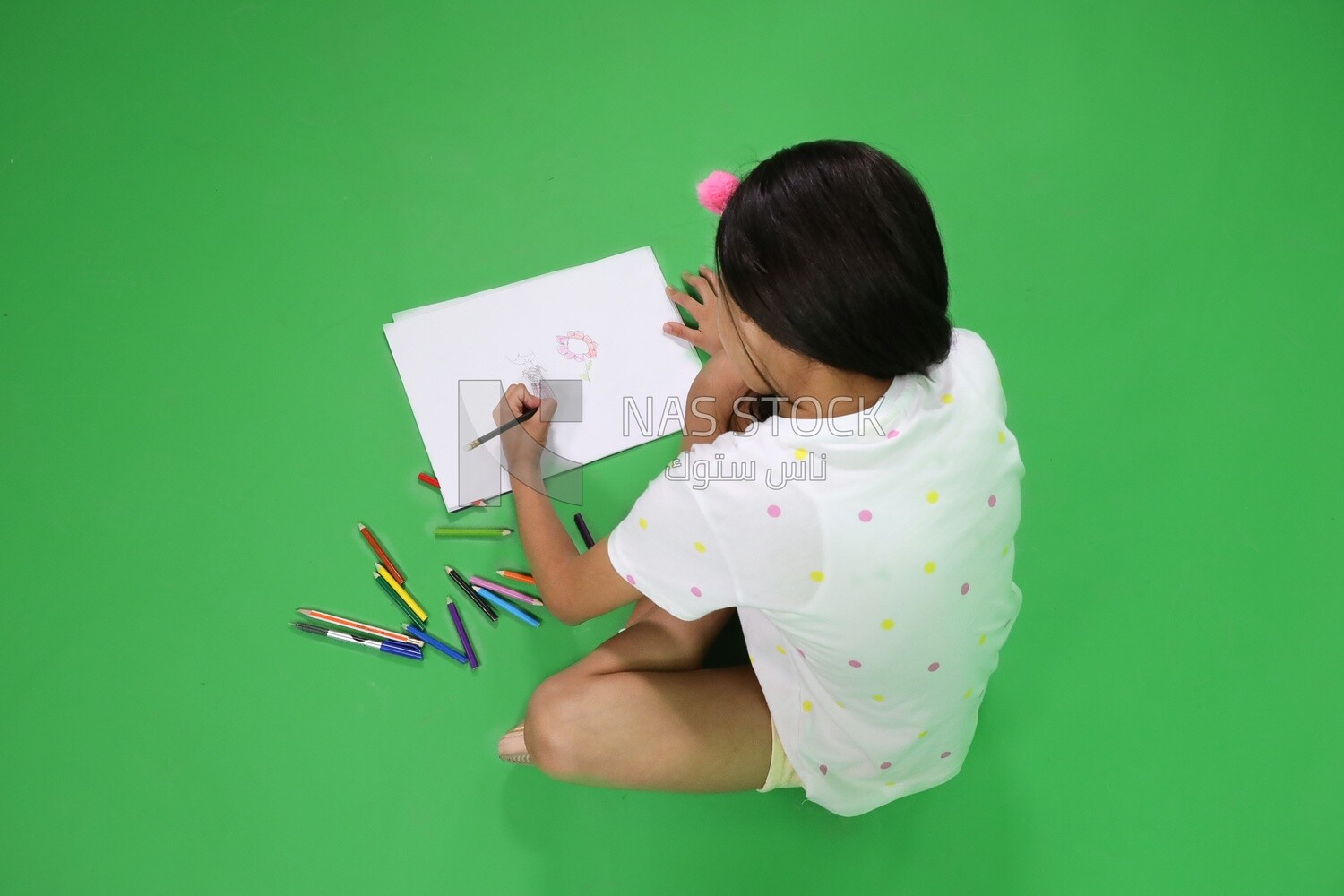 A girl sitting on the floor and drawing