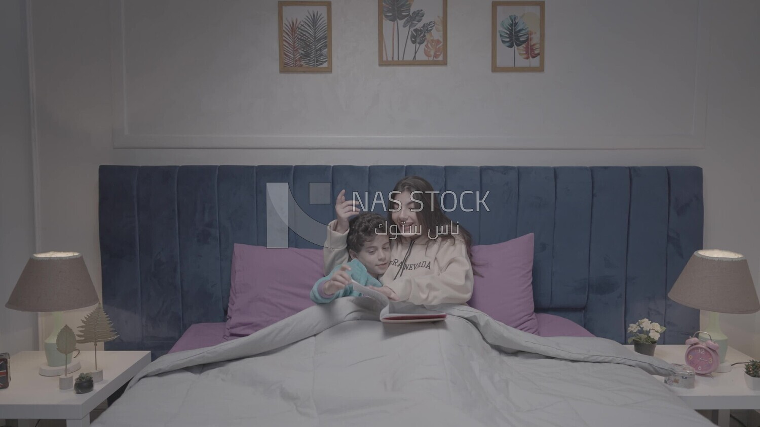 a woman reading a story to her son in bed