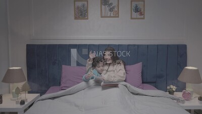 a woman reading a story to her son in bed