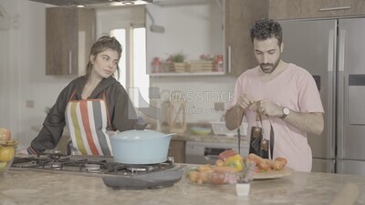 a man and a woman standing and cooking in the kitchen