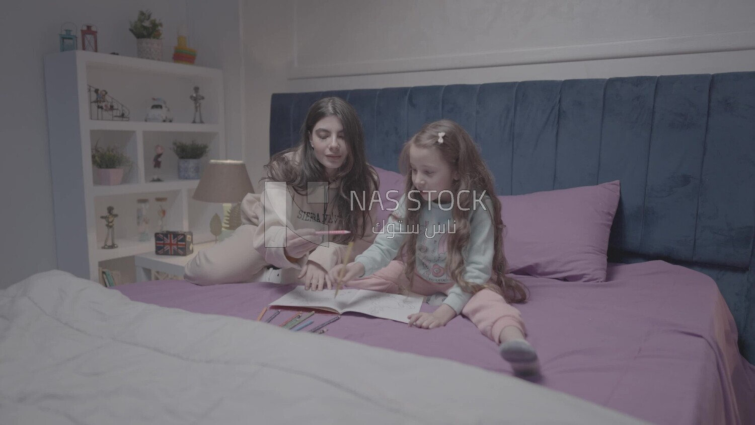 a mother with her daughter drawing together on the bed