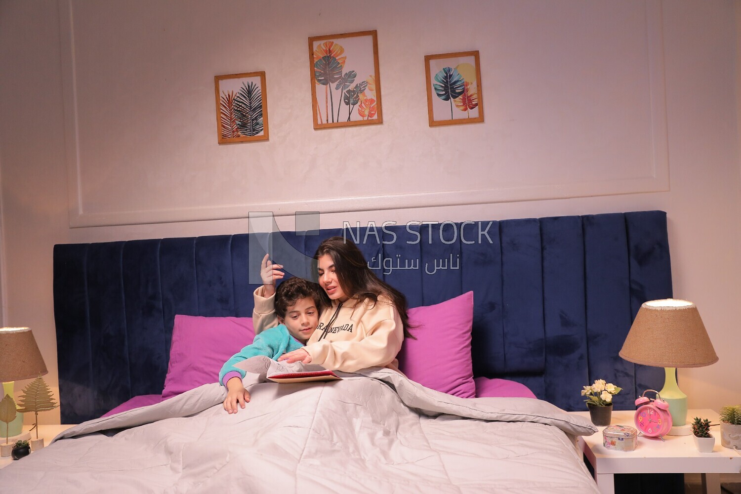a woman reading a story to her son in bed