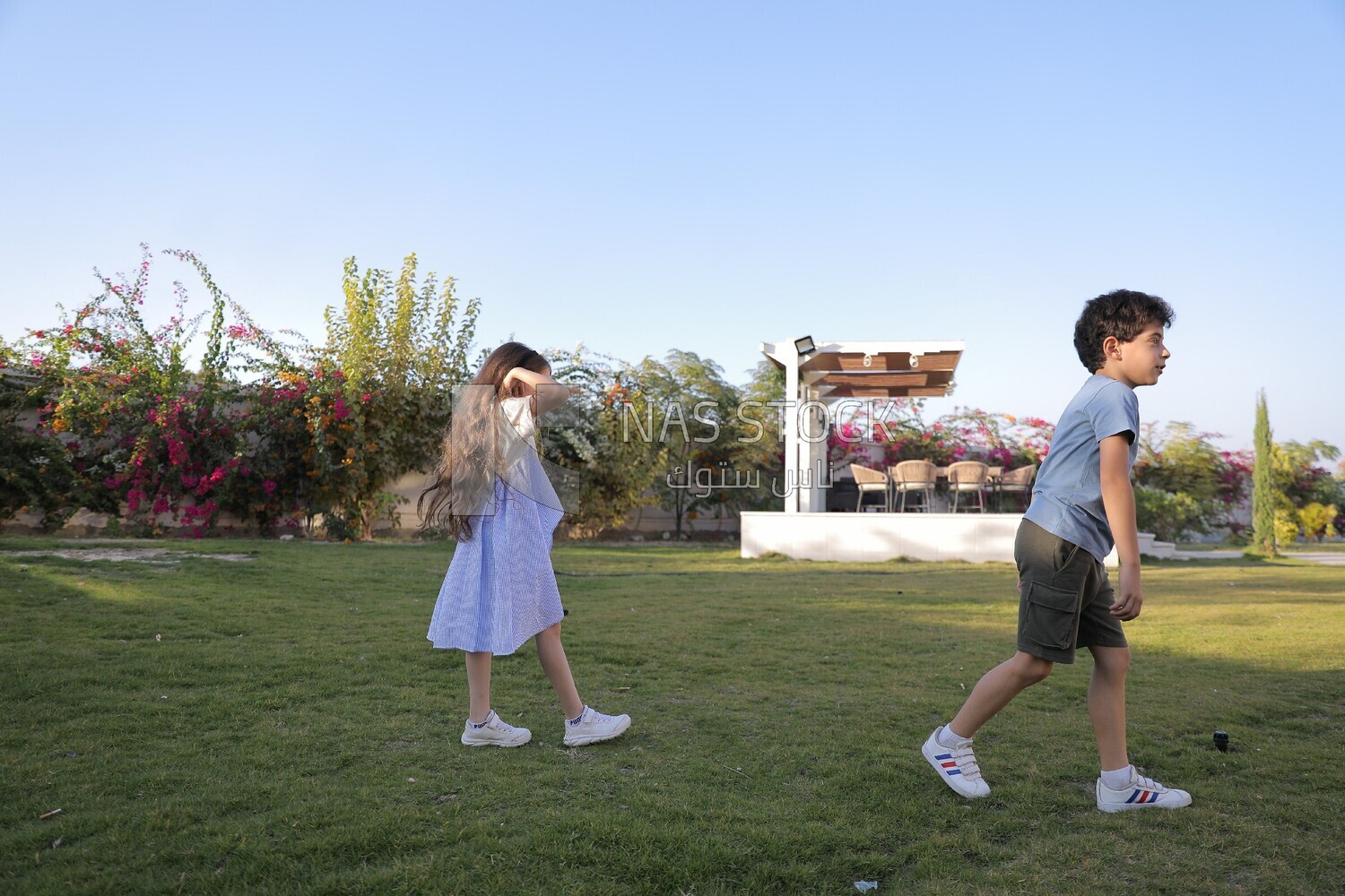 a brother playing football with his sister in the garden