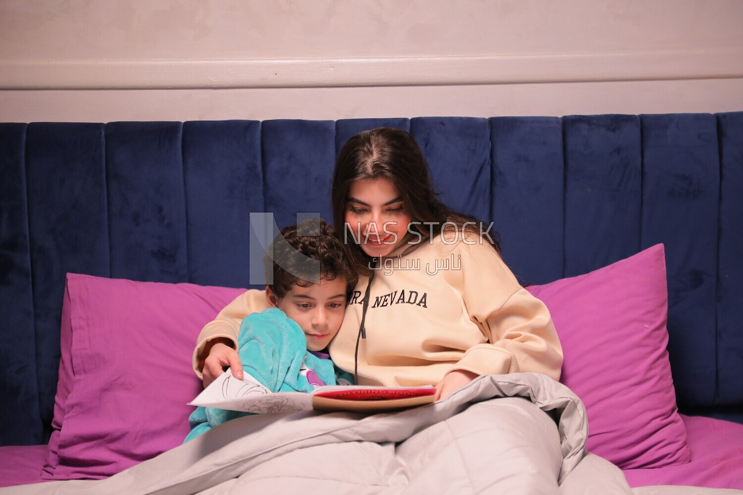 a woman reading a story to her son in bed