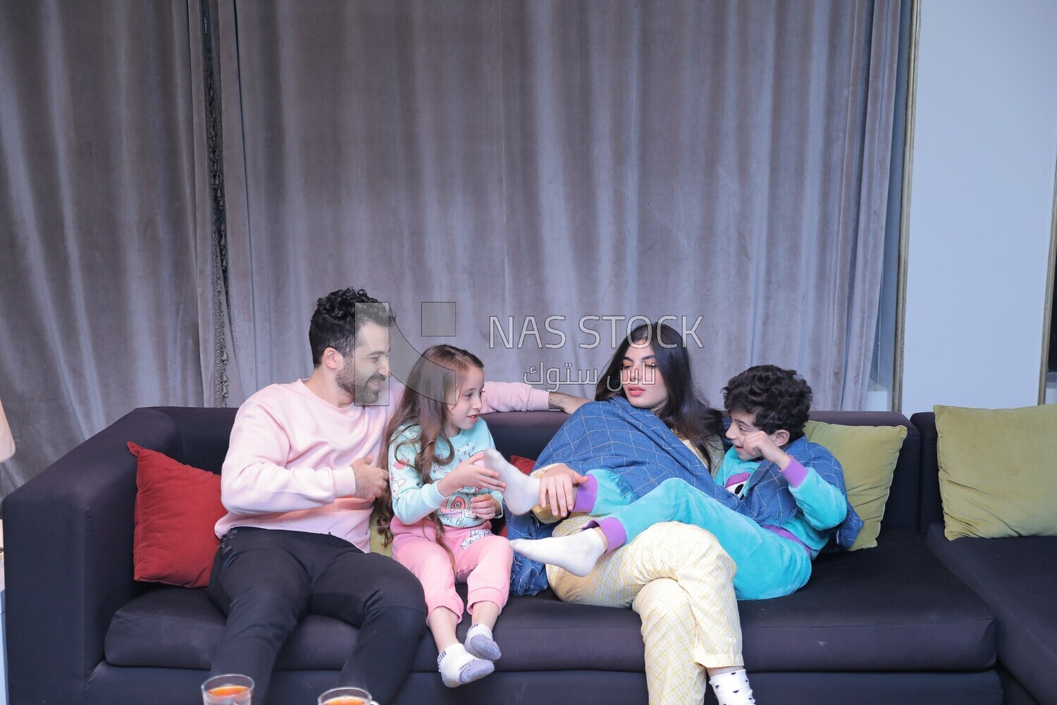 a family of four sitting on the sofa laughing