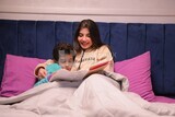 a woman reading a story to her son in bed