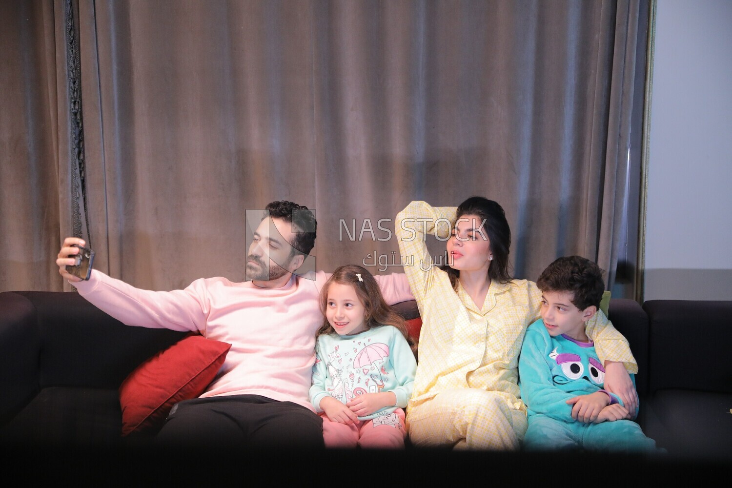 a family of four sitting on the sofa and taking a selfie