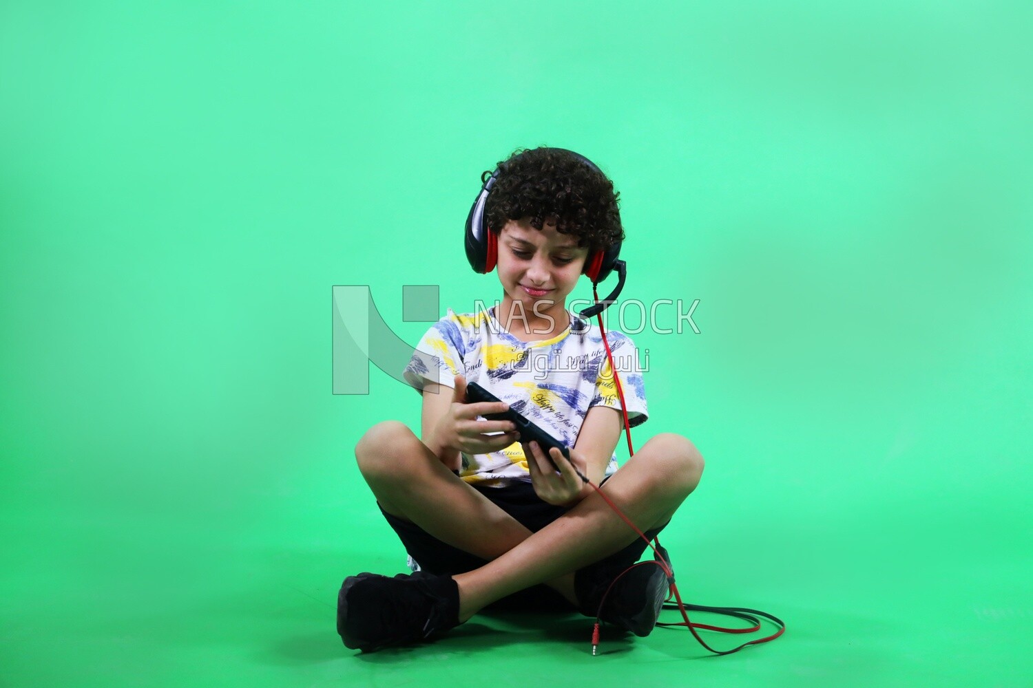 A boy holding a tablet and wearing a headphone