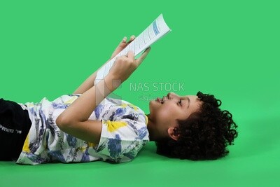 A boy reading a book and sleeping on the floor