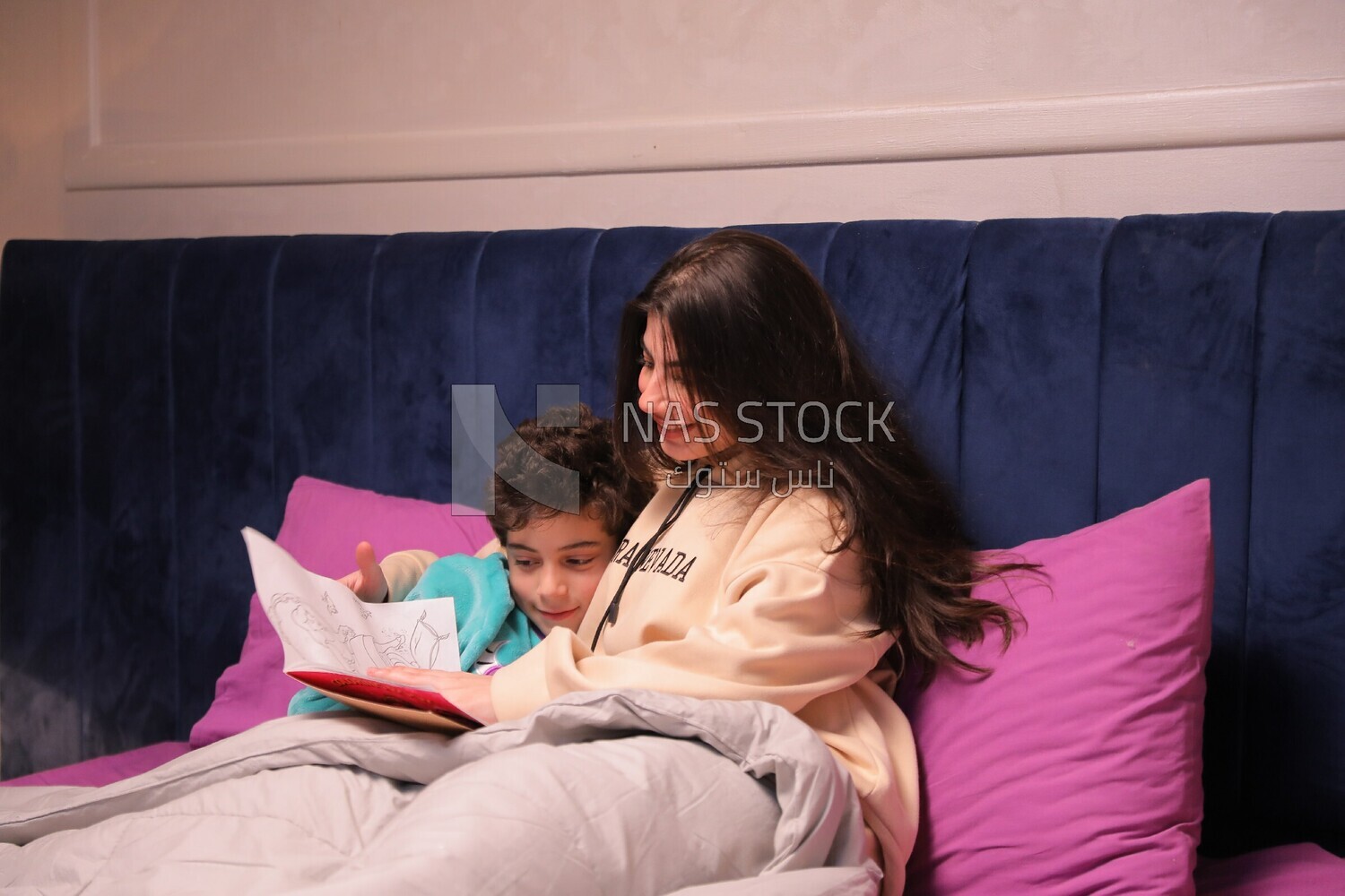 a woman reading a story to her son in bed
