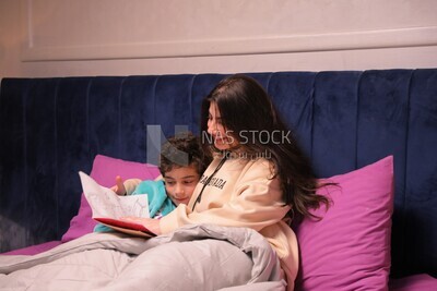 a woman reading a story to her son in bed