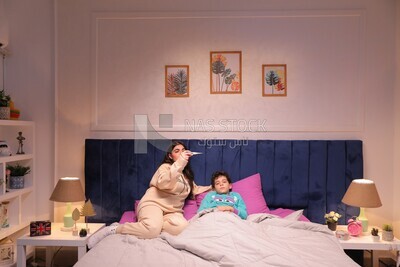 a woman sitting in bed takes her son&#39;s temperature