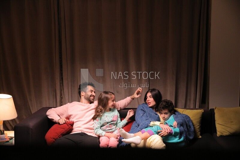 a family of four sitting on the sofa laughing