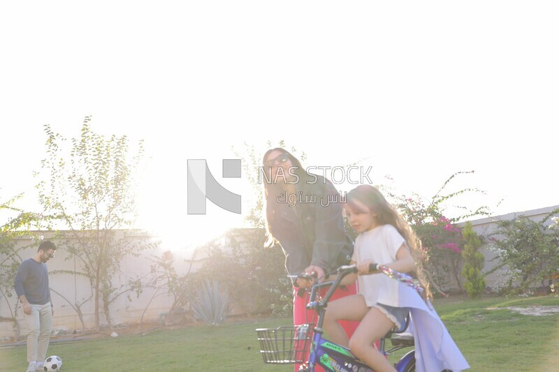 a woman helping her daughter ride a bike