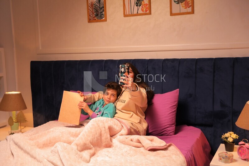 a woman reading a story to her child and taking a selfie in bed