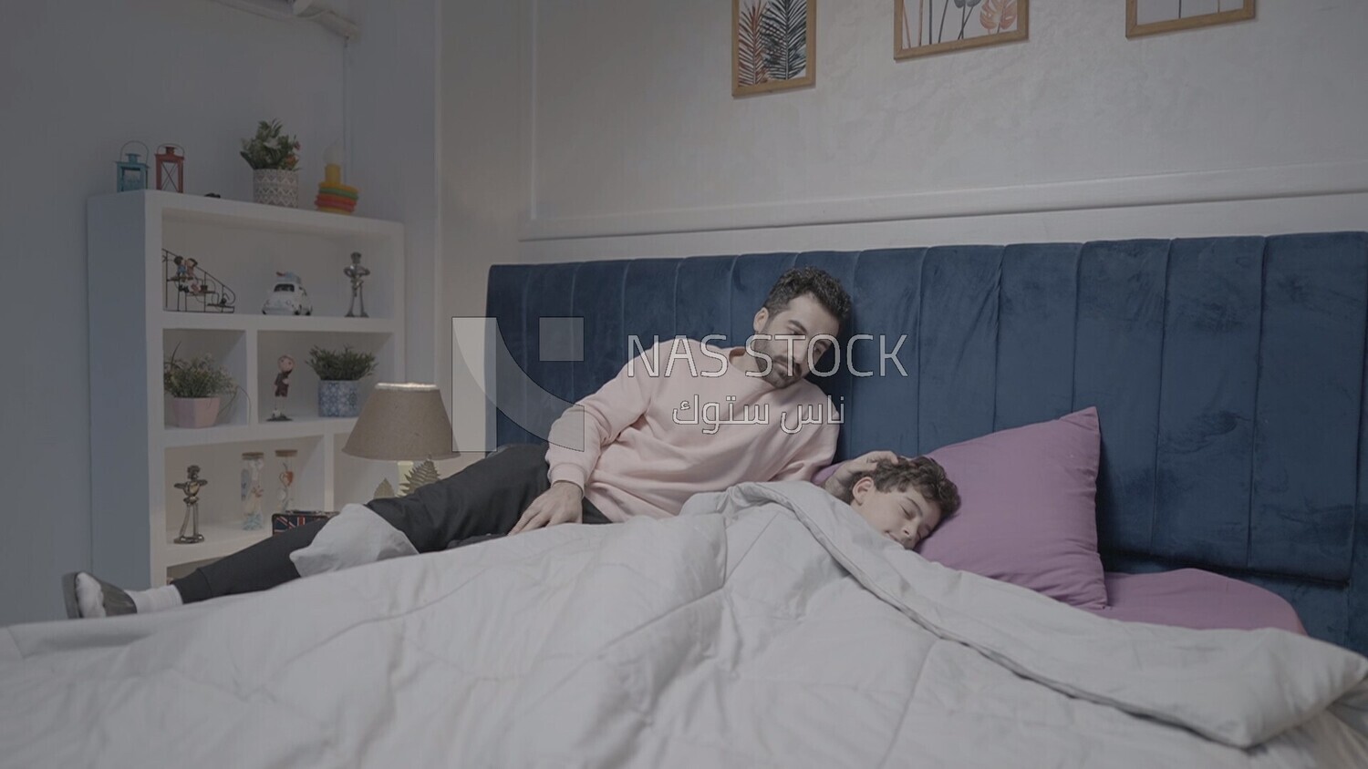 a father sitting on the bed during his boy&#39;s sleep