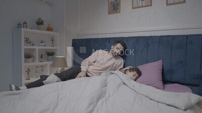 a father sitting on the bed during his boy&#39;s sleep