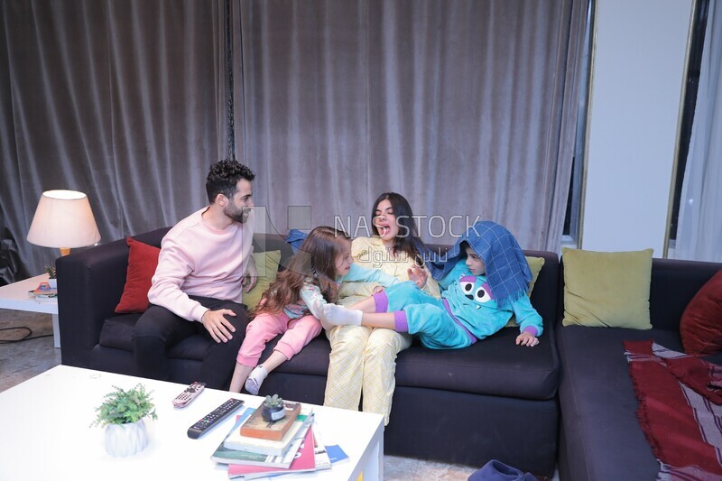 a family of four sitting on the sofa laughing