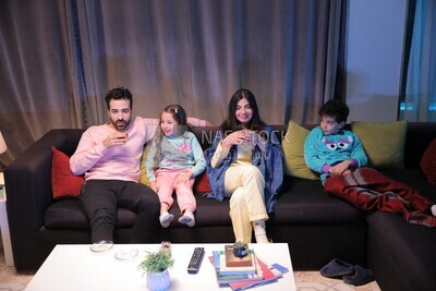 a family of four sitting on the sofa laughing and drinking a cup of tea