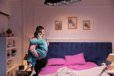 a father carrying his boy and putting him in bed
