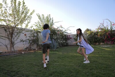 a brother playing football with his sister in the garden