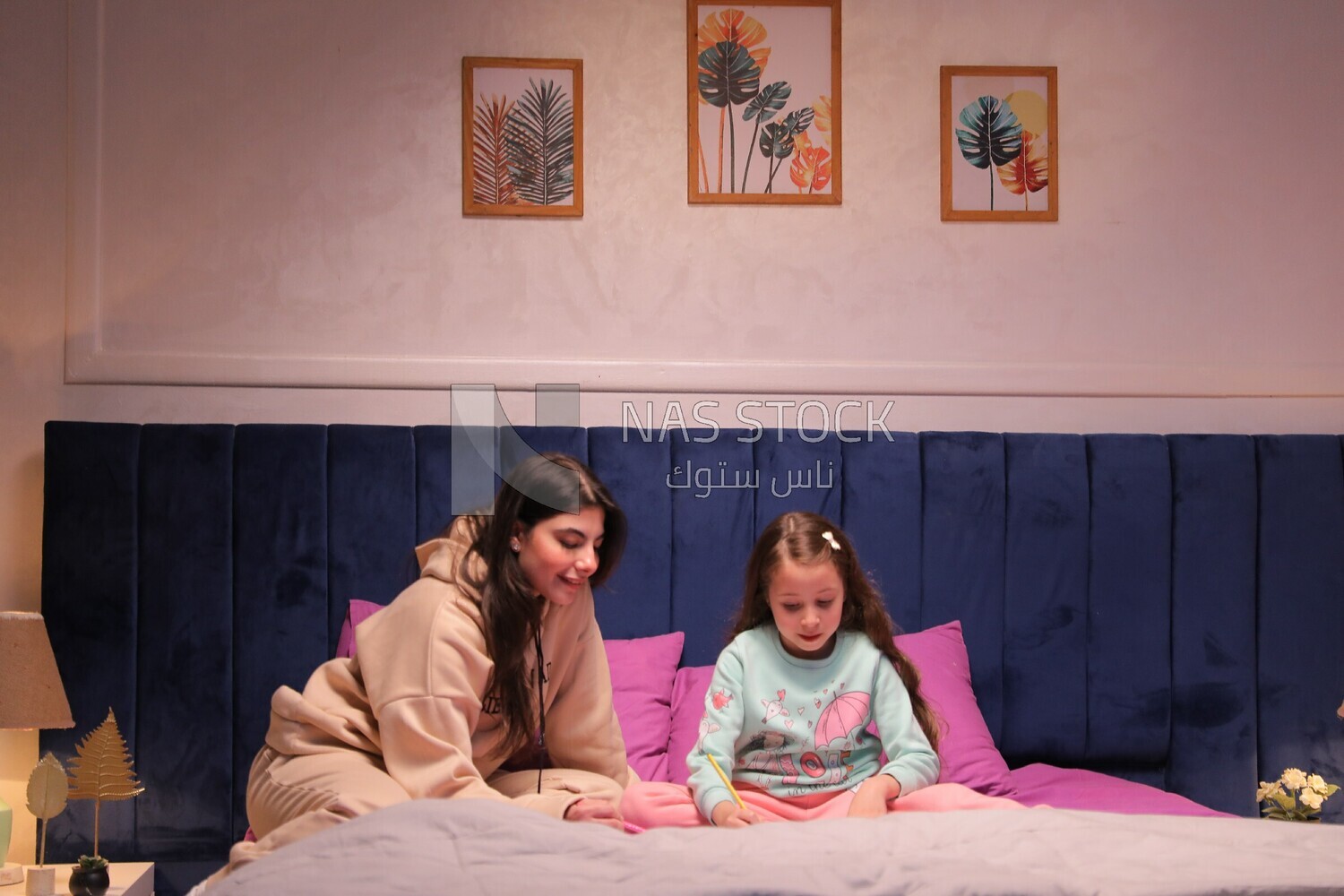 a mother with her daughter drawing together on the bed