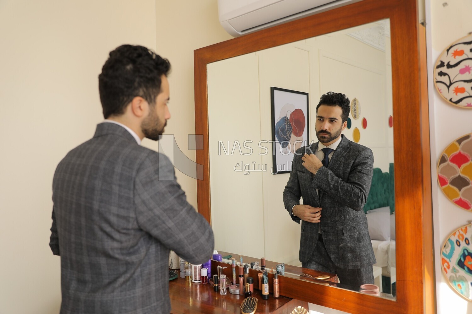 a man wearing a suit standing in front of the mirror