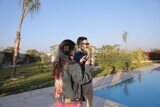 a husband with his wife standing in front of a swimming pool