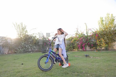 a girl riding a bike in the garden
