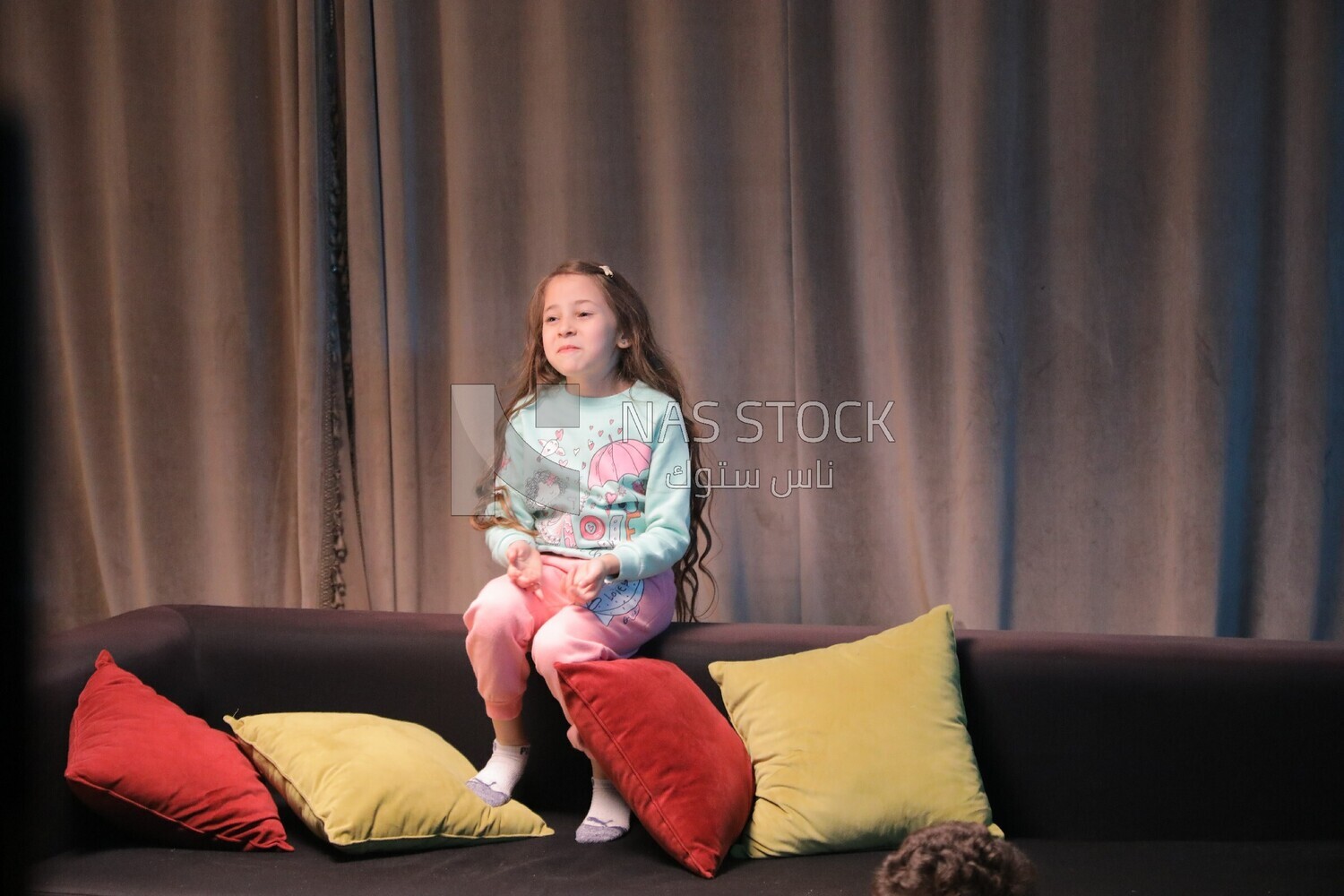 a girl sitting on the sofa in front of the television