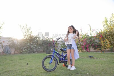 a girl standing beside a bike in the garden