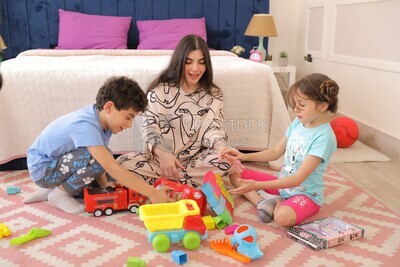 امراة تجلس مع اطفالها يلعبون 