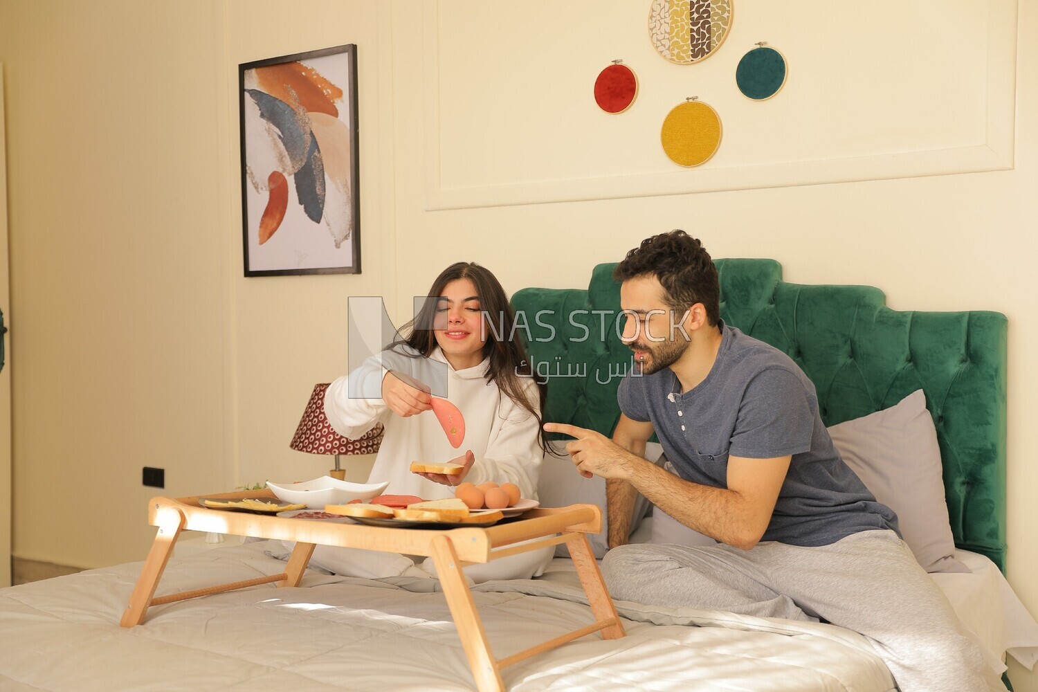 a man and a woman having breakfast on the bed