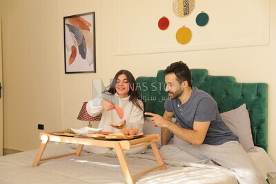 a man and a woman having breakfast on the bed