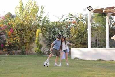brother playing football with his sister in the garden