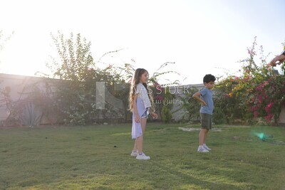 a brother playing football with his sister in the garden