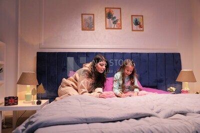 a mother with her daughter drawing together on the bed