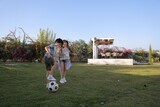 a brother playing football with his sister in the garden