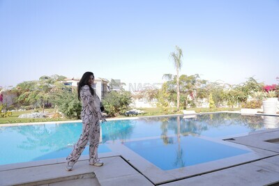 a woman standing in the garden beside a swimming pool